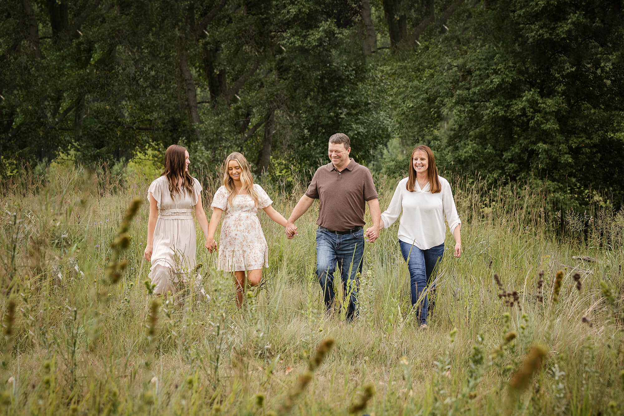 Fall family session with family of four walking through tall grasses.