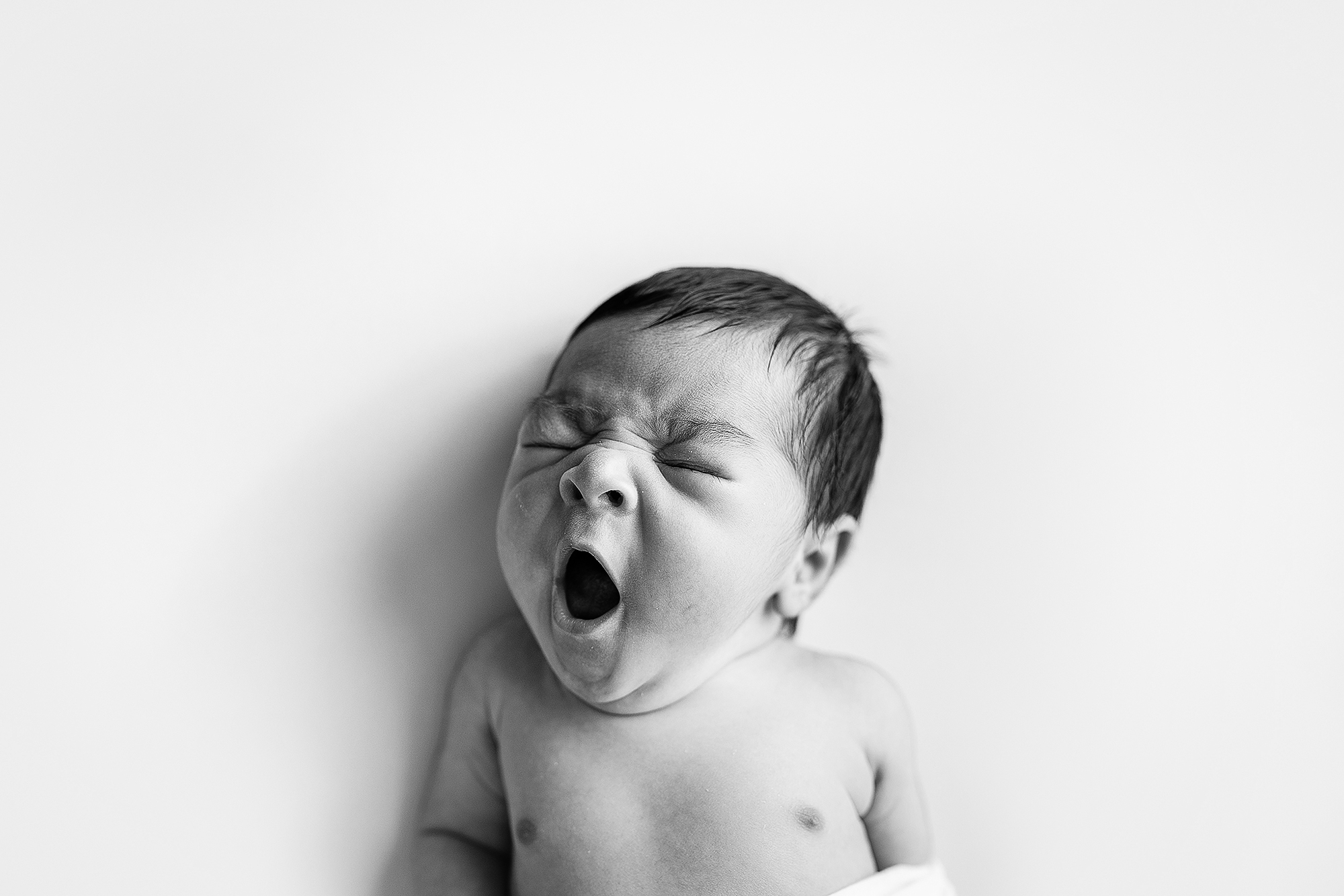 Newborn boy yawning during his studio portrait session.