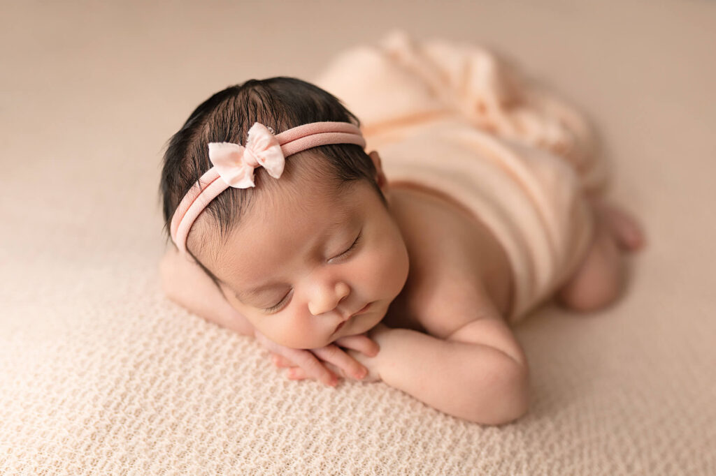 Newborn girl with pink headband posed during her baby photo session.
