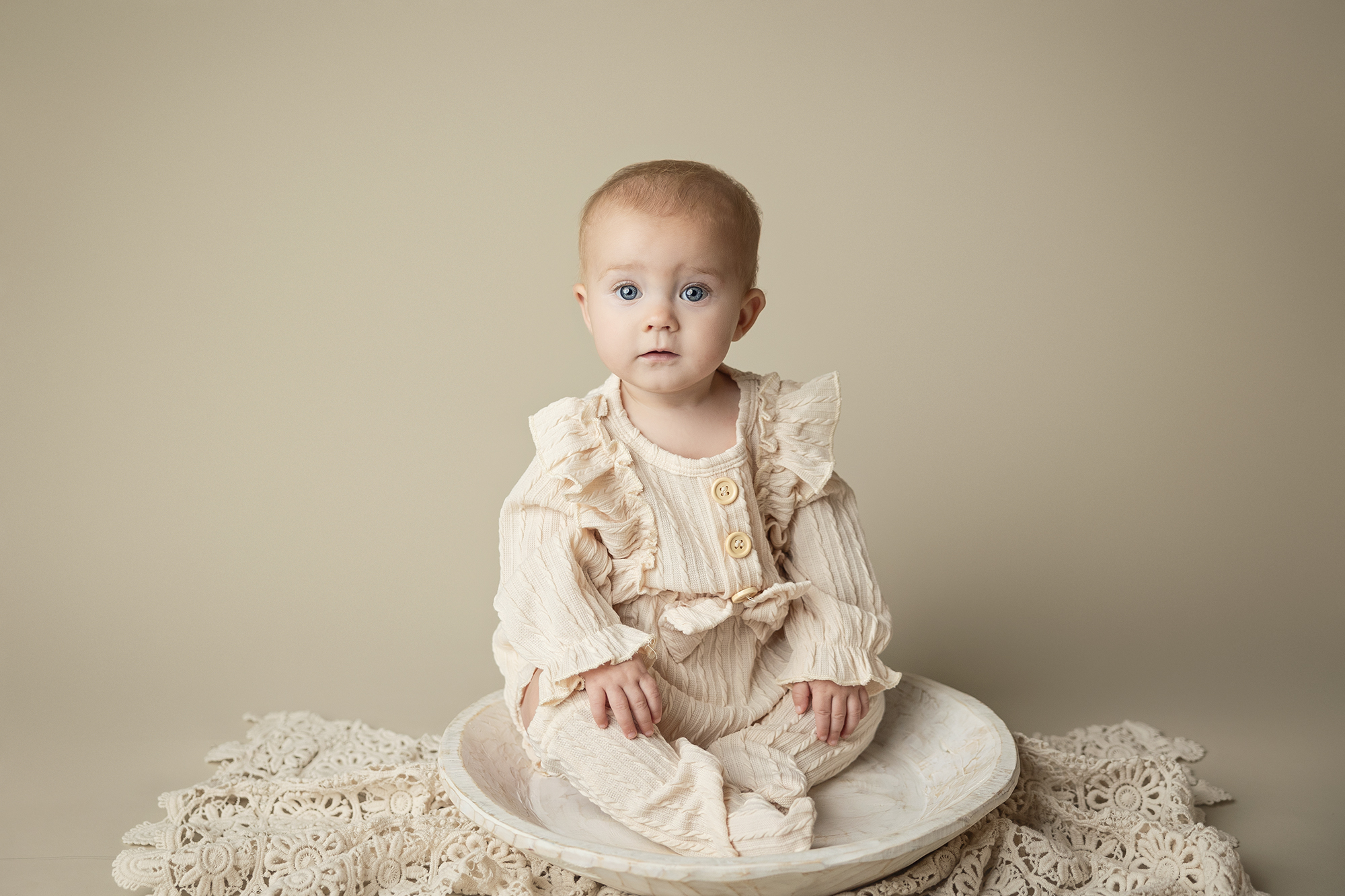 Beautiful baby girl wearing a cream outfit with matching leggings.