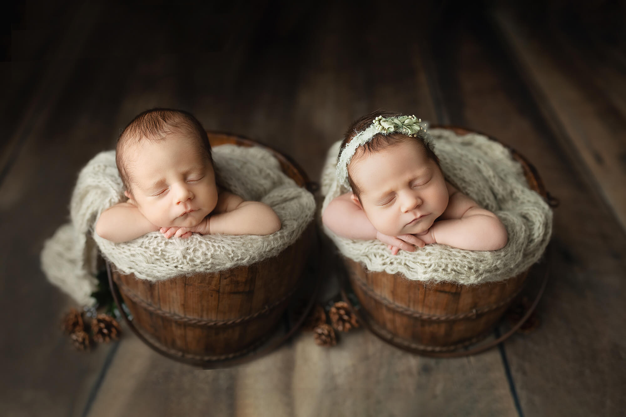 Twin babies sleeping peacefully in wooden buckets taken during their newborn session.