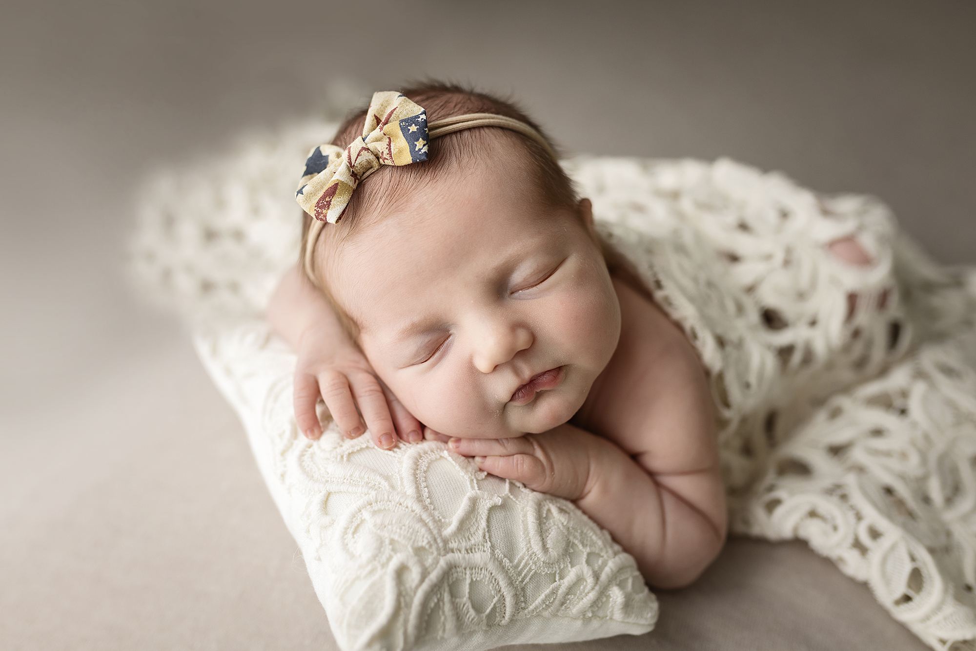 Baby girl asleep on a crocheted pillow.