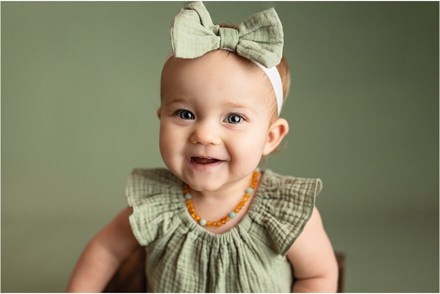 9 month old baby girl in a green romper for her milestone photo session.