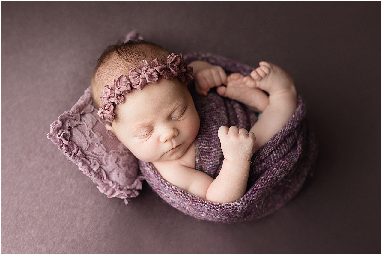 Newborn girl on purple wrapped by her newborn photographer, Jennifer Brandes.