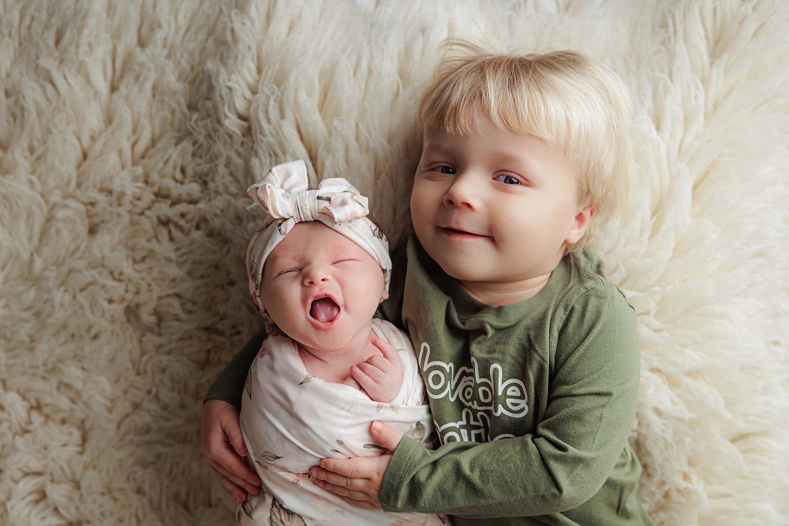 Newborn baby wrapped up for pictures with her big brother.
