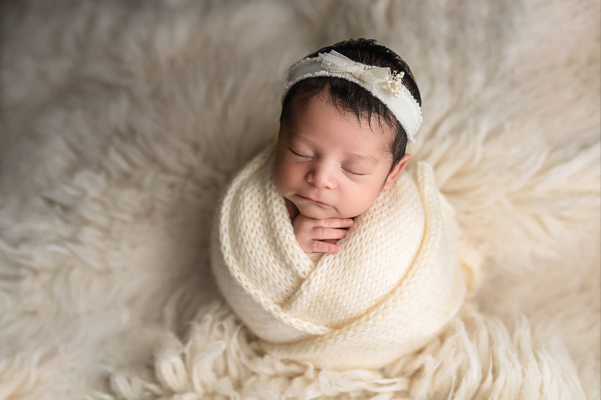 Baby girl wrapped up in a hand knitted wrap during her newborn sesison.