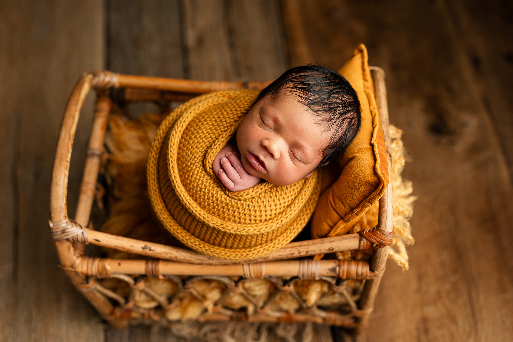 Swaddled newborn in a bamboo basket - cozy prop newborn photography Minnesota.