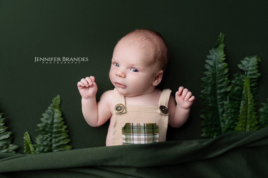 Newborn boy posed on dark green during his baby photo session in Southern Minnesota.