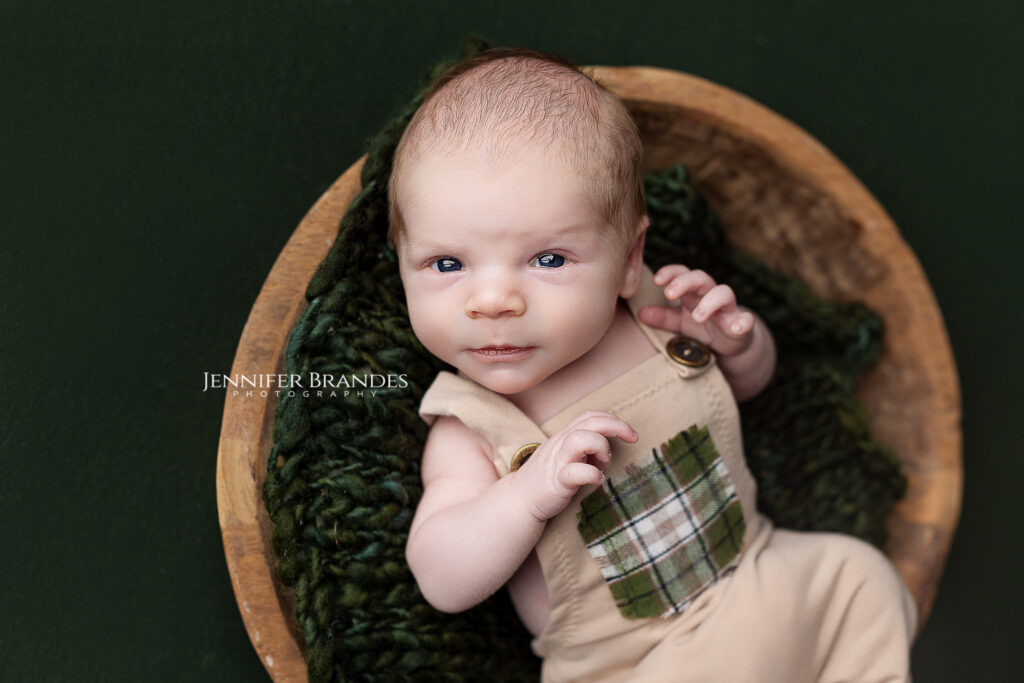 Newborn boy wearing khaki overalls during his session in New Ulm, Minnesota.